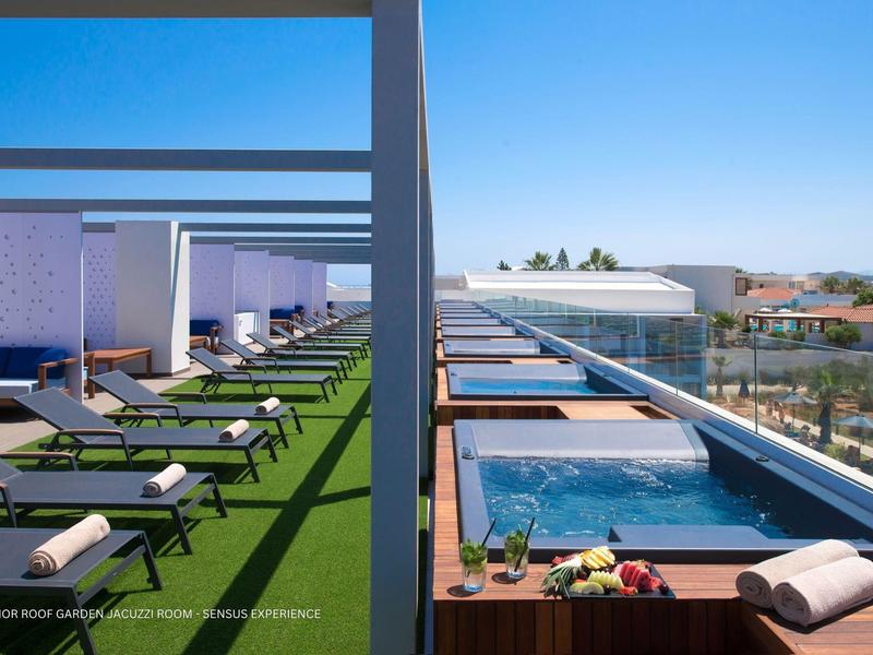 Terraza en la azotea con tumbonas y jacuzzis privados en un hotel bajo cielos despejados.