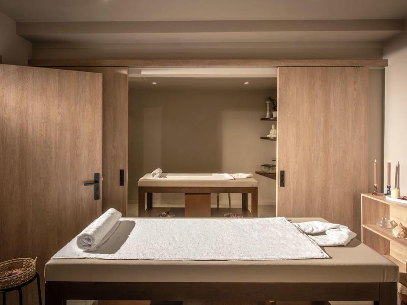 Stanza spa luminosa con lettini per massaggi e mobili in legno dal design caldo.