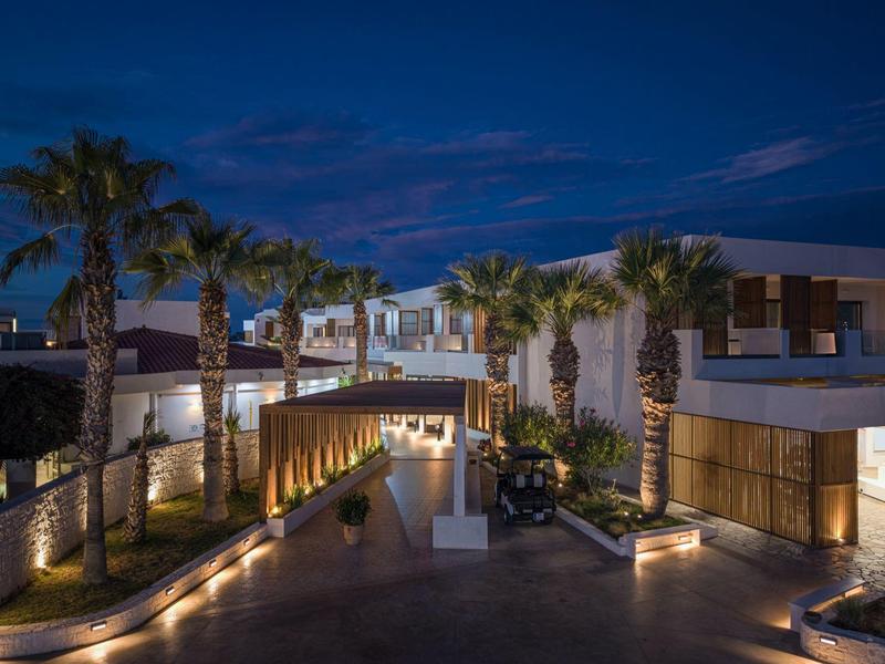 Hotel moderno con ingresso illuminato e palme di notte.