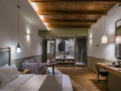 Chambre d'hôtel confortable avec lit double, bureau, canapé et éclairage chaleureux.