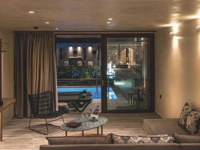 Salon confortable avec vue sur une piscine éclairée à travers une porte coulissante en verre.