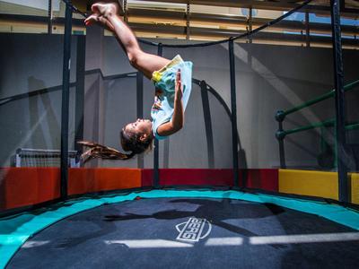 Un garçon fait un salto arrière sur un trampoline dans une salle.