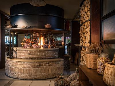 Przytulny bar hotelowy z ciepłym kominkiem, drewnianymi półkami i dekoracyjnymi koszami wewnątrz.