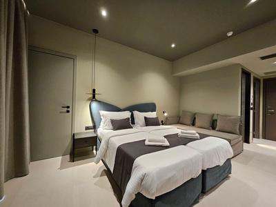 Chambre d'hôtel moderne avec lit double, canapé et éclairage tamisé.