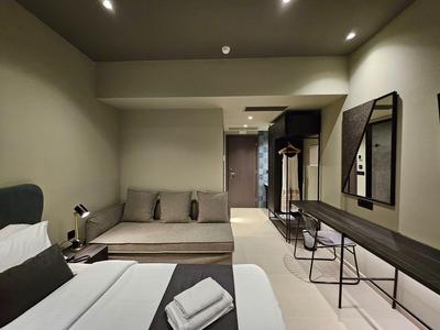 Chambre d'hôtel moderne avec lit, canapé, bureau et design minimaliste.