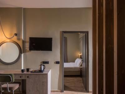 Chambre d'hôtel moderne avec bureau, miroir et vue sur la chambre à coucher.