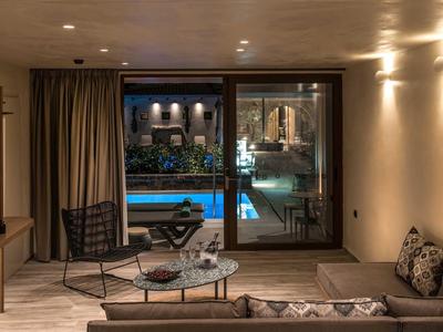 Chambre d'hôtel élégante avec vue sur la piscine extérieure éclairée la nuit.