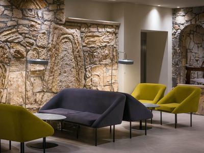 Espace lounge d'hôtel moderne avec fauteuils confortables et mur en pierre décoratif.