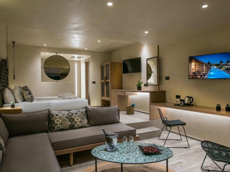 Chambre d'hôtel moderne avec lit double, canapé et coin salon.