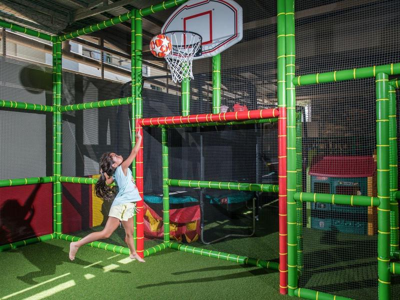 Enfant jouant et sautant dans une salle de jeux intérieure avec panier de basket.