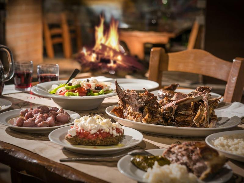 Une table dressée avec divers plats de viande et accompagnements devant une cheminée.