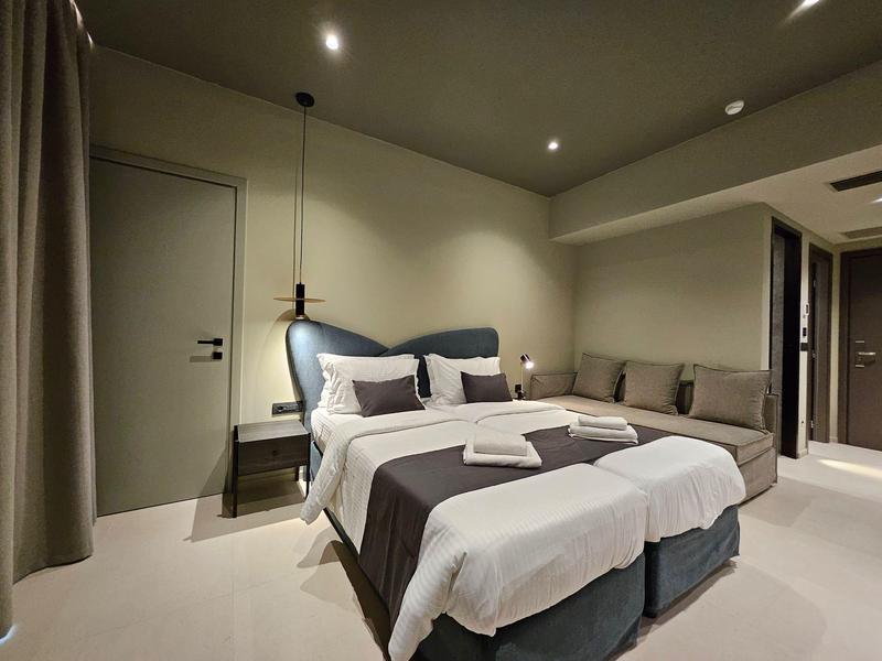 Chambre d'hôtel moderne avec lit double, canapé et éclairage tamisé.