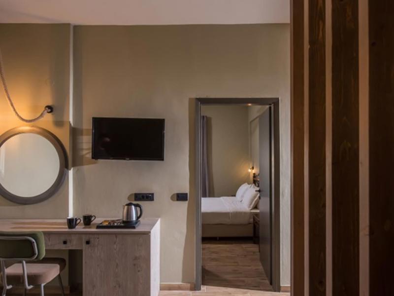 Chambre d'hôtel moderne avec bureau, miroir et vue sur la chambre à coucher.