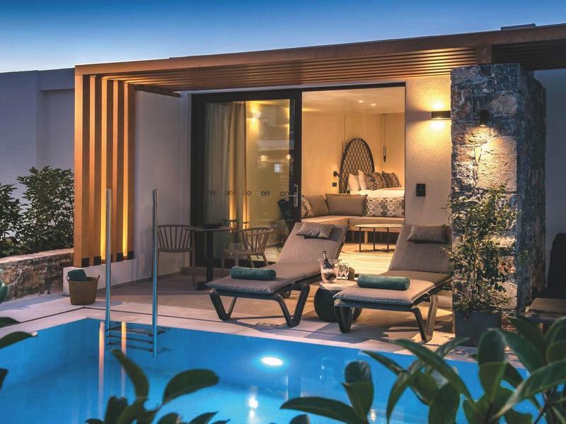 Lodge d'hôtel moderne avec piscine éclairée et chaises longues relaxantes sur la terrasse.