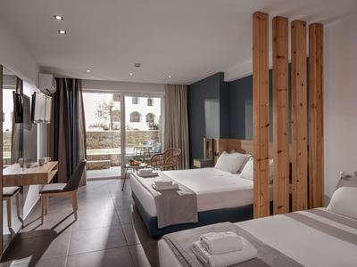 Modernes Hotelzimmer mit zwei Betten, Schreibtisch, Fernseher und großem Fenster zur Terrasse.