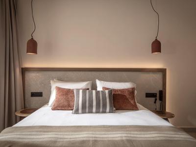 Modernes Hotelzimmer mit großem Bett, zwei Nachttischen und warmem Licht.