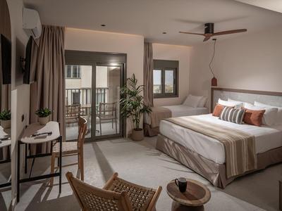 Gemütliches Hotelzimmer mit großem Bett, Balkon, Stühlen und modernem Dekor.