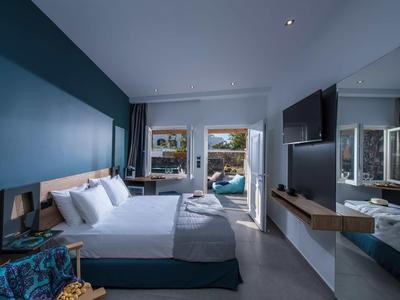 Modern hotel room with double bed, TV, and access to a terrace with table and chairs.