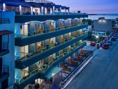 Modern hotel with illuminated balconies and terrace in the evening by the sea.