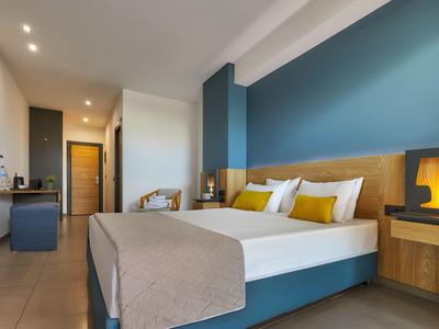 Camera d'hotel moderna con letto matrimoniale, parete blu, mobili in legno e illuminazione accogliente.