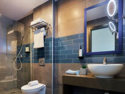 Bagno moderno con doccia a filo pavimento, WC, lavandino e specchio illuminato
