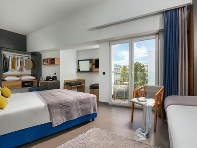Camera d'hotel moderna con letto matrimoniale, scrivania, balcone e area salotto.