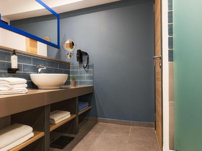 Bagno moderno con lavabo su piano, asciugamani e parete accentuata blu.