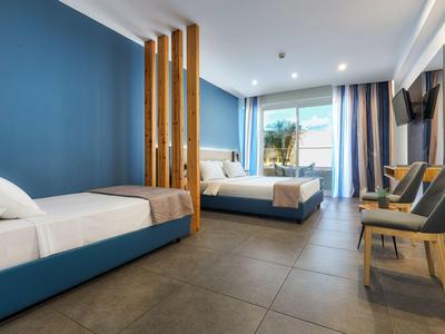 Camera d'hotel moderna con due letti, pareti blu e balcone con vista sul mare.