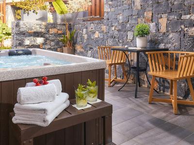 Accogliente area esterna con vasca idromassaggio, sedie in legno, tavoli e asciugamani freschi.