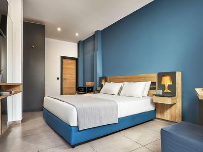 Camera d'hotel moderna con accenti blu, letto grande e design minimalista.