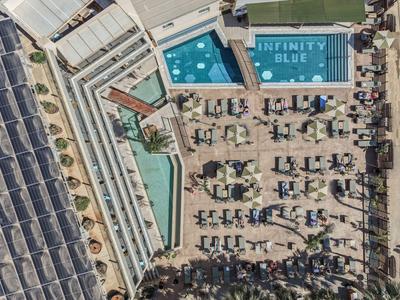 Vogelperspektive eines Hotelpools mit angrenzenden Liegestühlen und Solaranlagen