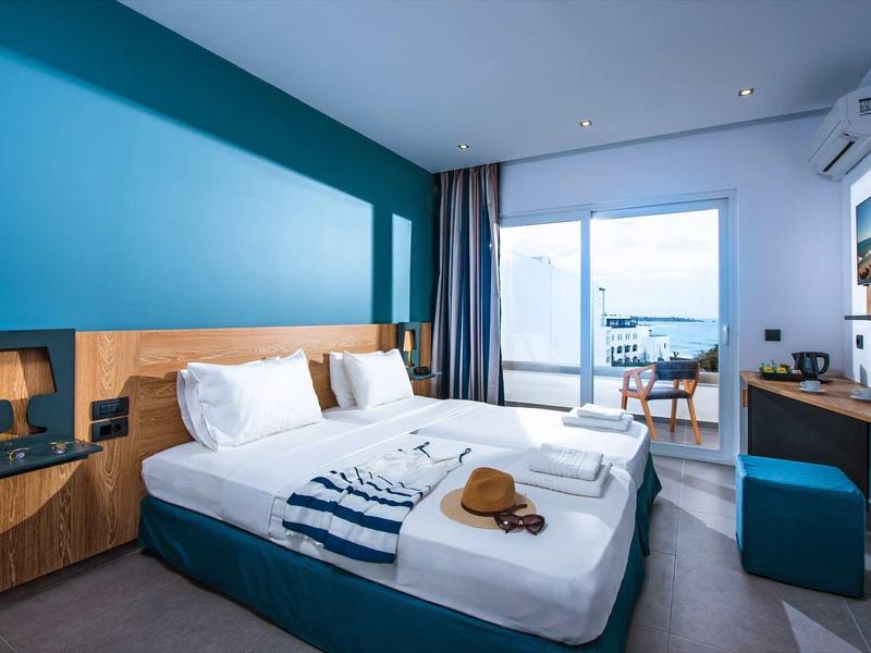 Modern hotel room with double bed, balcony, and sea view.