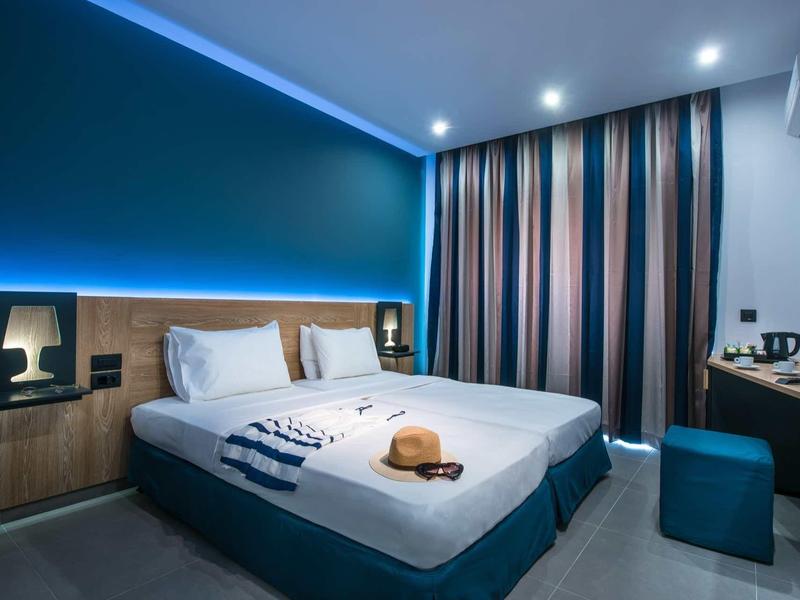 Modern hotel room with double bed, blue accents, and striped curtains.