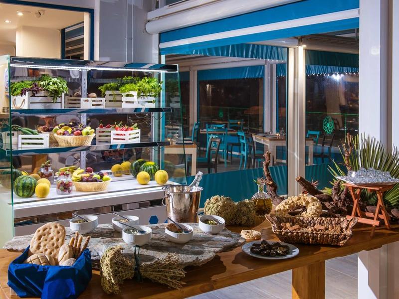 Buffet with fresh fruit and bread in a hotel restaurant overlooking a terrace.