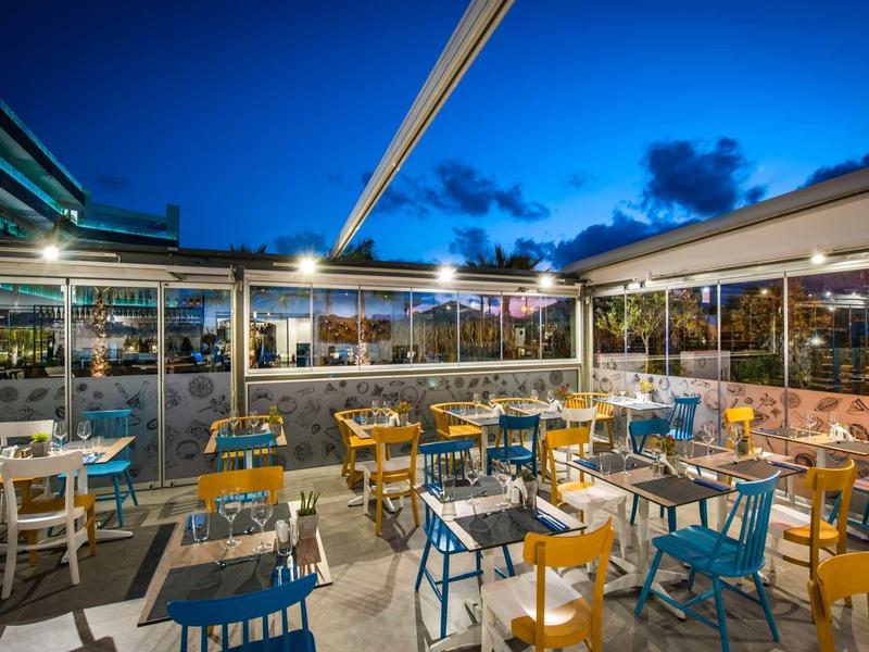 Outdoor restaurant area with colorful chairs and tables at dusk.