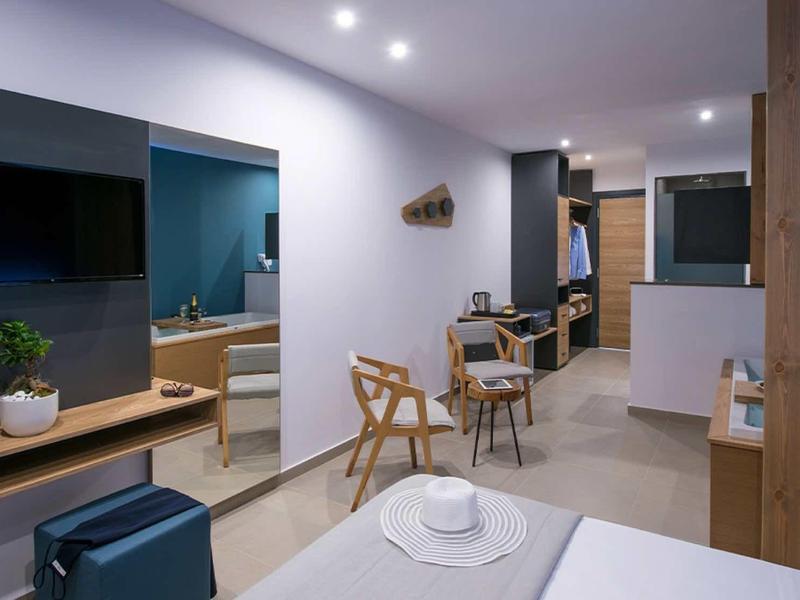 Modern hotel room with seating area, TV, and workspace.