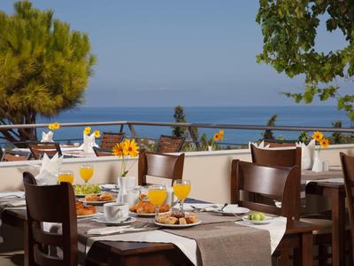 Terrasse mit gedeckten Tischen und Blick auf das Meer bei klarem Himmel