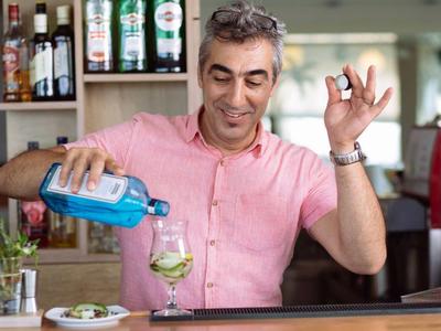 Mann in rosa Hemd gießt Getränk in Glas an Bar