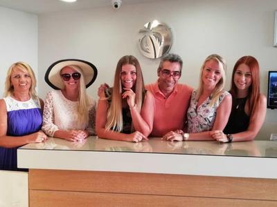 Sechs Personen stehen an einem hellen Empfangstresen in einem Hotel.