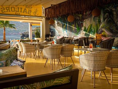 Accogliente area bar con mobili in rattan e vista mare al tramonto.