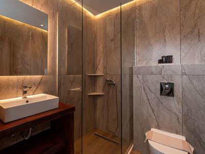 Modernes Badezimmer mit großen grauen Fliesen, Glasdusche und Holzwaschtisch mit rechteckigem Waschbecken.