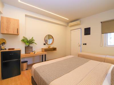 Modern eingerichtetes Hotelzimmer mit Doppelbett, Schreibtisch, Spiegel und Minibar.