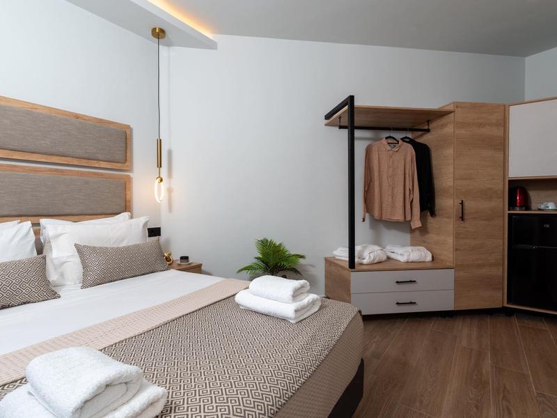 Modern eingerichtetes Hotelzimmer mit Doppelbett, Schrank und gefalteten Handtüchern