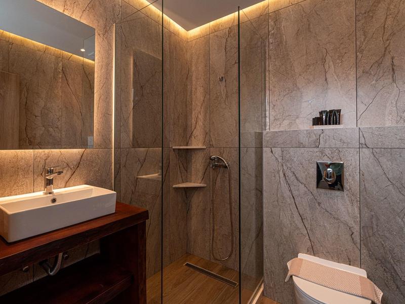 Modernes Badezimmer mit großen grauen Fliesen, Glasdusche und Holzwaschtisch mit rechteckigem Waschbecken.