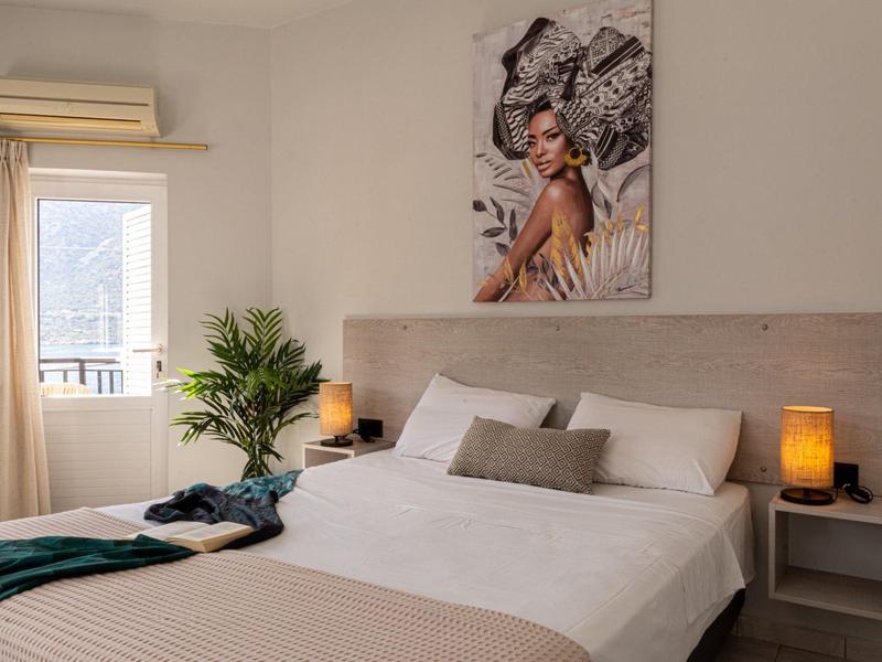 Hell eingerichtetes Schlafzimmer mit großem Bett, Pflanzen und Kunst an der Wand.