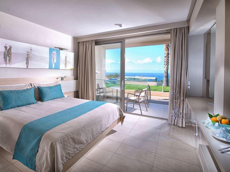 Nowoczesny pokój hotelowy z podwójnym łóżkiem i balkonem z widokiem na morze.