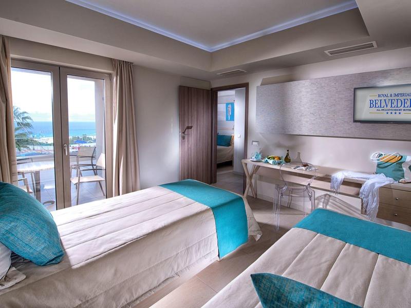 Nowoczesny pokój hotelowy z dwoma łóżkami pojedynczymi i balkonem z widokiem na morze.