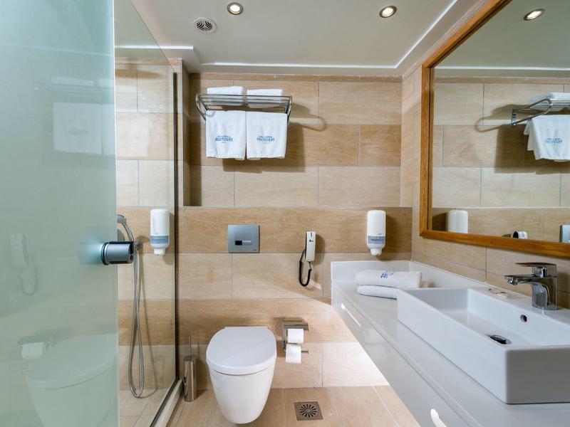 Nowoczesna łazienka z prysznicem, toaletą, umywalką i dużym lustrem.