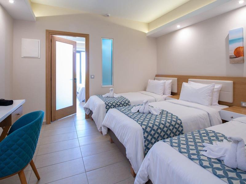 Potrójny pokój hotelowy z trzema łóżkami, stylowym biurkiem i nowoczesnym wystrojem w ciepłych kolorach.