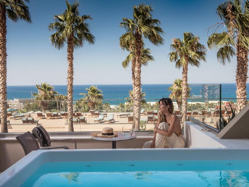 Widok z tarasu z basenem na palmy i morze przy słonecznej pogodzie.